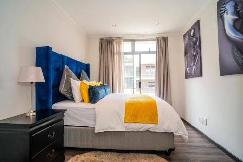 1 dormitorio con 1 cama con almohadas azules y amarillas en The Escalante, en Johannesburgo