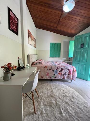 a bedroom with a bed and a desk with a computer at Casa com Piscina in Canavieiras