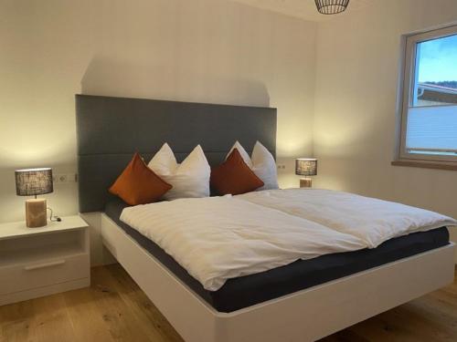 a bedroom with a large white bed with orange pillows at Geißhof in Rettenberg