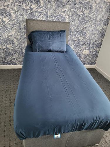 a bed with a blue comforter and pillows at Larchmont House in Leicester