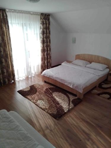 a bedroom with two beds and a wooden floor at Pensiunea Edia in Borşa