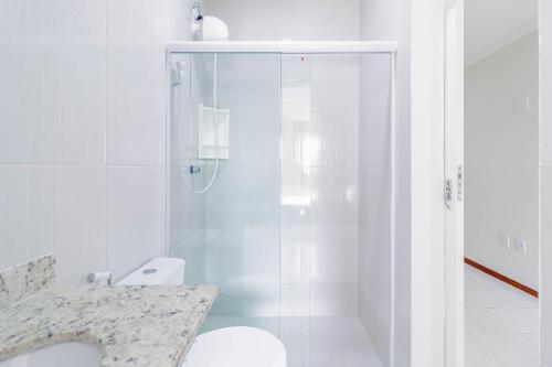 een witte badkamer met een douche en een toilet bij PFL03 Apto 3 Quartos a 250m da Praia in Salvador