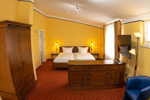 a bedroom with a bed and a wooden dresser with a bed sidx sidx sidx at Kaisergarten Hotel I Restaurant in Neuenrade