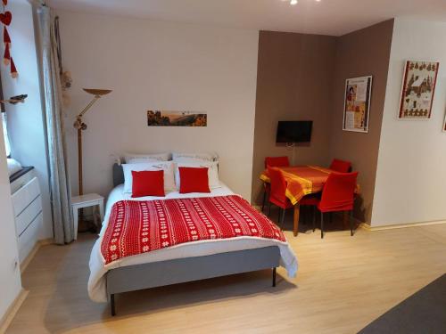 a bedroom with a bed with red pillows and a table at Le BUBELE au coeur du centre médiéval et vignoble in Ribeauvillé