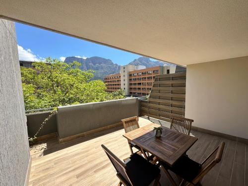 balcón con mesa de madera y sillas con vistas en Newlands Peak Apartments en Ciudad del Cabo
