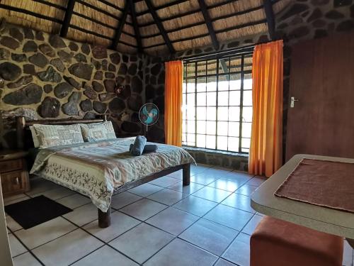 1 dormitorio con cama y pared de piedra en Moletani Game Ranch en Kareefontein