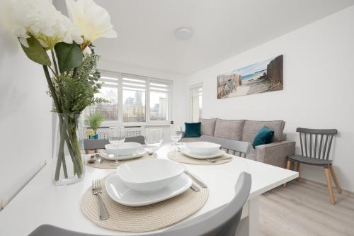 a white dining room with a table with a vase of flowers at Elegant Apartment in the centre of Gdynia by Renters in Gdynia