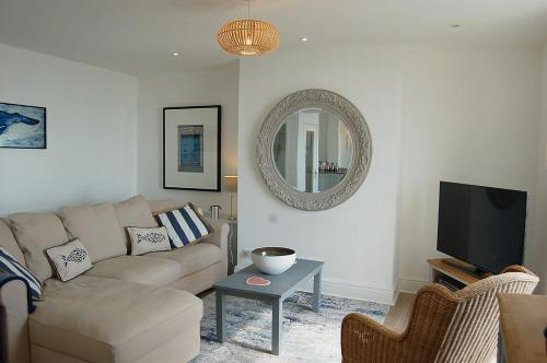 a living room with a couch and a mirror at Driftwood Designer Apartment in Tywyn