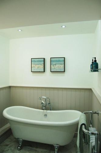 a bath tub in a bathroom with two pictures on the wall at Driftwood Designer Apartment in Tywyn