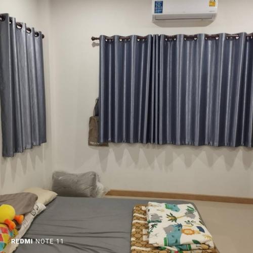 um quarto com uma cama com cortinas azuis em Bann Sukjai em Kanchanaburi