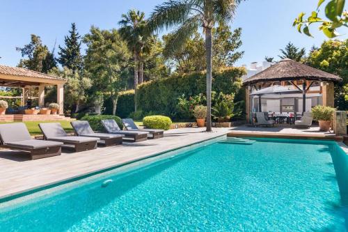 een zwembad met stoelen en een prieel bij 7 Room Villa Mansion - Sleeps 16+ in San Roque