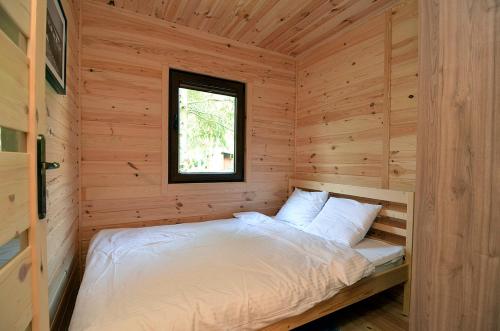 uma cama num chalé de madeira com uma janela em Bajkowy Las em Mielno