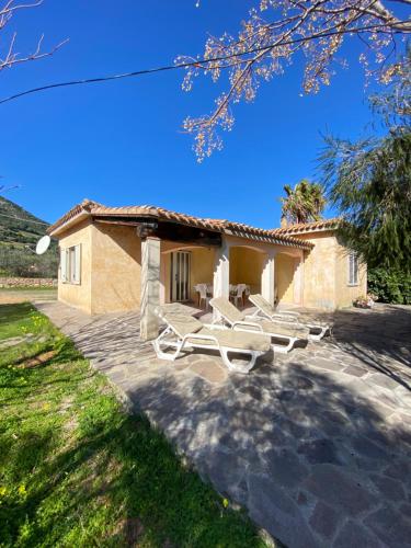 a house with two lounge chairs and a building at Villa Verde in Tertenìa