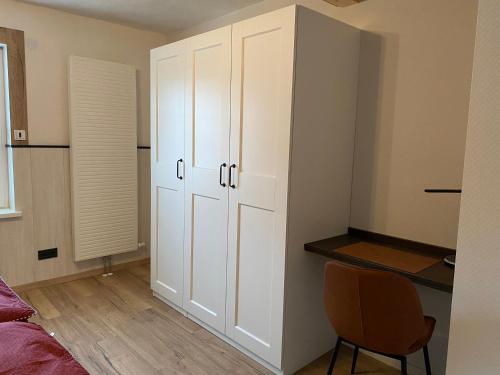 a bedroom with white cabinets and a chair next to a bed at Haus Mariechen Whg 2 in der Nähe zum Silbersee mit gemütlicher Terrasse & Sauna in Frielendorf