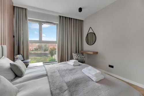 Un dormitorio con una gran cama blanca y una ventana en Flatbook - City Center SPA Apartments Grano Residence with Riverview & Parking en Gdansk