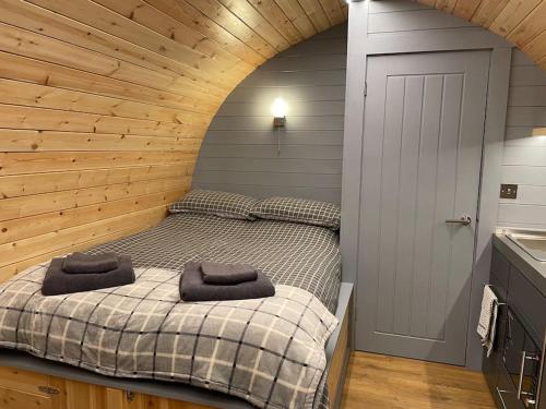a bedroom with a bed in a wooden wall at Bonny Wee Snug - Pod in Spean Bridge in Spean Bridge