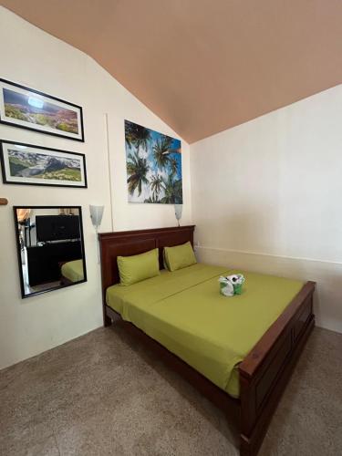 Un dormitorio con una cama con sábanas verdes y una ventana en Ice Bear Bar & Tourist Inn, en Dauis