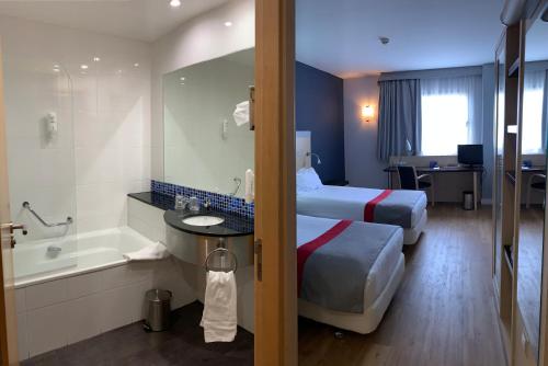 a hotel room with two beds and a bath tub at Holiday Inn Express Vitoria by IHG in Vitoria-Gasteiz