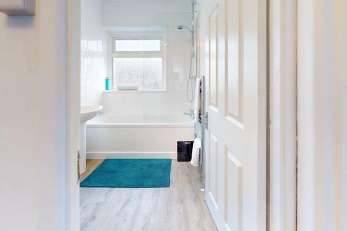 a bathroom with a white tub and a blue rug at CONeN Dagenham Home in Goodmayes