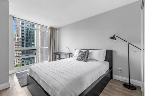 a white bedroom with a bed and a large window at 2 BR Waterfront Condo Downtown w/ free Parking in Toronto