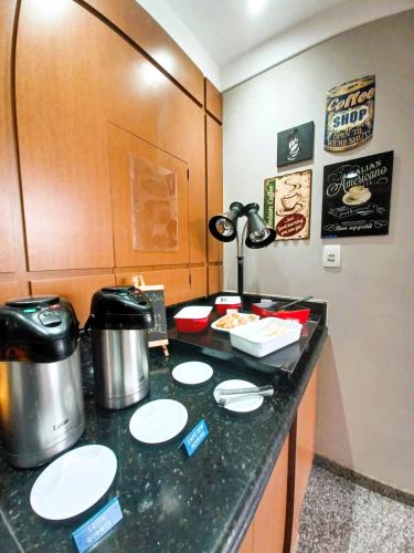 a kitchen with a counter with plates and food at Hotel Riviera in Araçatuba
