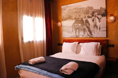 a bedroom with a bed with a picture on the wall at Riad ait Ben Haddou in Aït Ben Haddou