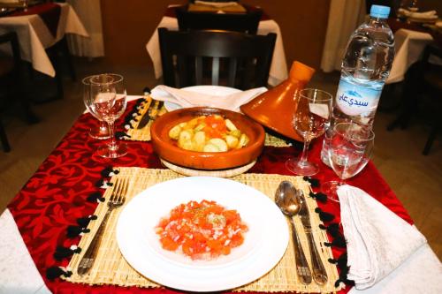 a table with a plate of food and wine glasses at Riad ait Ben Haddou in Aït Ben Haddou