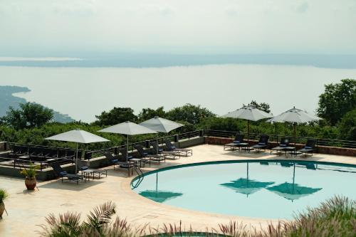 a swimming pool with tables and chairs and umbrellas at Mantis Akagera Game Lodge in Akagera