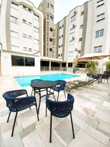 a patio with tables and chairs next to a pool at Hotel Riviera in Araçatuba