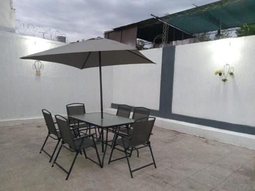 einen Tisch mit Stühlen und einem Sonnenschirm auf einer Terrasse in der Unterkunft Amplia Casa Familiar en G Cruz in Godoy Cruz