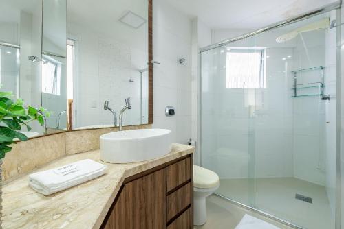 een badkamer met een wastafel en een glazen douche bij Apto confortável a 4min do mar RTA042 in Balneário Camboriú