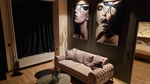 a living room with a couch and pictures on the wall at TRESOR Delux Apartment in Osijek