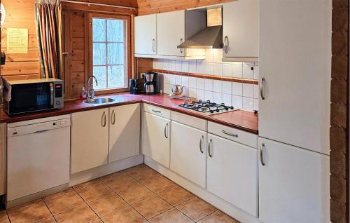 a kitchen with white cabinets and a stove top oven at Nice Home In Neede With Sauna in Gelselaar