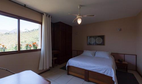 ein Schlafzimmer mit einem Bett und einem großen Fenster in der Unterkunft Hotel Dominguez Master in Nova Friburgo