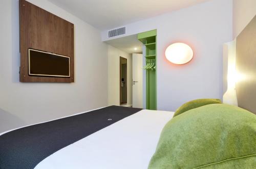 a bedroom with a bed and a tv on the wall at Campanile Annemasse Gare– Genève in Annemasse