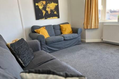 a living room with a blue couch and yellow pillows at Collingwood House by StayStaycations in Bristol