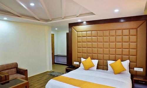 um quarto com uma cama grande e almofadas amarelas em FabHotel Whistling Winds em Manali