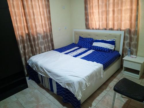Schlafzimmer mit einem Bett mit blauer und weißer Bettwäsche in der Unterkunft Treasure apartment in Lagos
