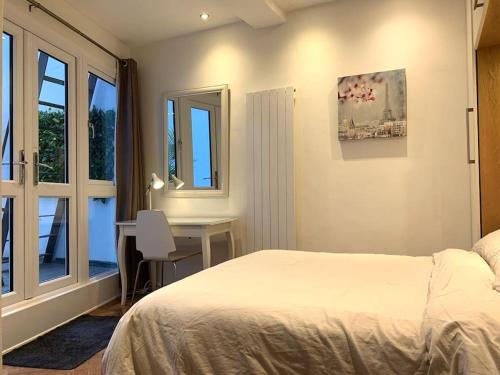 una camera con letto, scrivania e finestre di Hyde Park 3bed with patio as seen on TV House Hunters International a Londra