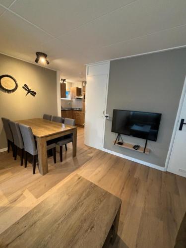 a dining room with a table and a flat screen tv at Puur Texels 9a in De Koog