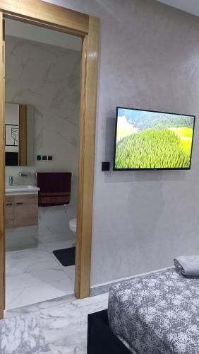 a bathroom with a television hanging on the wall at Escalade BAYTI 2 in El Jadida