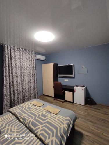 a bedroom with a bed and a desk and a tv at Гостевой дом LIMANN in Odesa