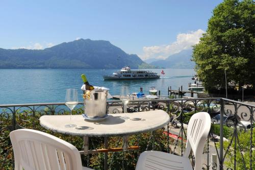 - une table avec une bouteille de vin et un bateau dans l'eau dans l'établissement Seehof Hotel Du Lac, à Weggis