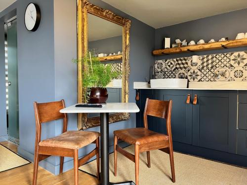 a dining room with a table and two chairs and a mirror at Rockmount Rooms & Apartment in Tavistock