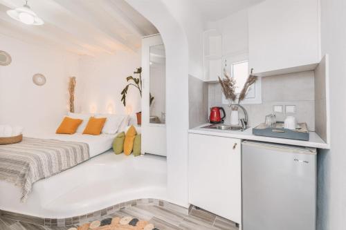 a white room with a bed and a kitchen at Dibellee Mykonos Studios in Glastros