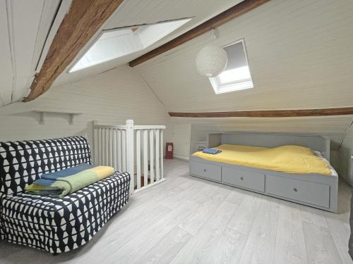 sypialnia z łóżkiem i kanapą na poddaszu w obiekcie Escapade Moretaine - L'Echappée au charme d'antan w mieście Moret-sur-Loing