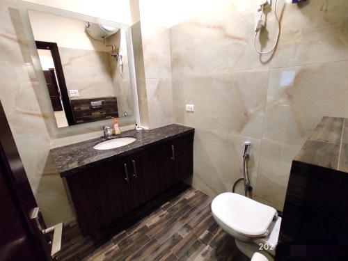 a bathroom with a toilet and a sink and a mirror at When In Gurgaon - ARTEMIS HOSPITAL 1 Min Walk, FORTIS & MEDANTA 4 Mins Drive in Gurgaon