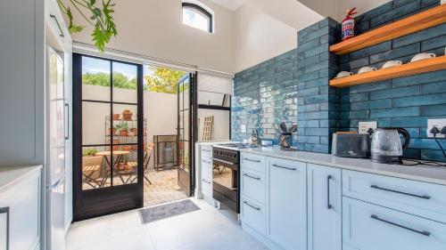uma cozinha com armários brancos e paredes de tijolos azuis em Franschhoek Colours em Franschhoek