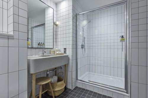a white bathroom with a sink and a shower at One Hundred Shoreditch in London