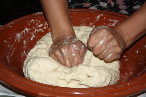 a person kneading dough in a red bowl at Riad Yamcha in Meknès